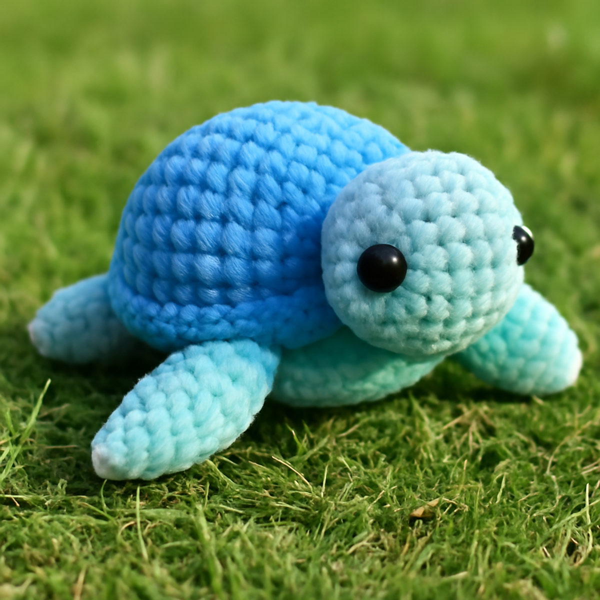 A finished plush turtle amigurumi, approximately 6-8 inches in diameter, made with pastel blue and soft mint yarn, featuring large safety eyes and a round shell.